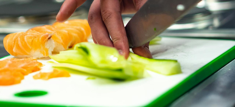 Osoba koja seče namirnice na plastičnoj dasci sa seckanje 